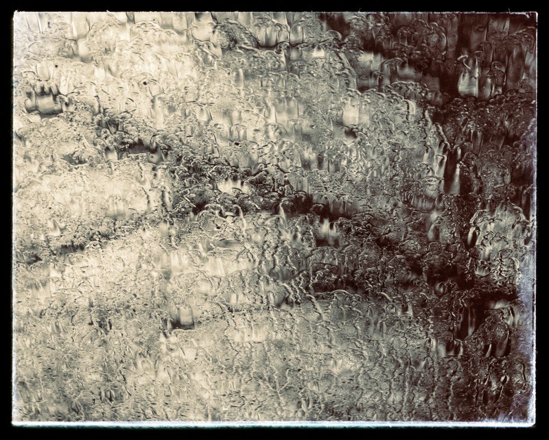 View through high window through opaque ice covered glass to winter tree branches. 