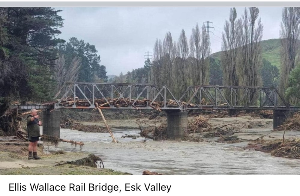 Bridge over river after a flood has gone through, the bridge is full of broken trees from forestry slash. 