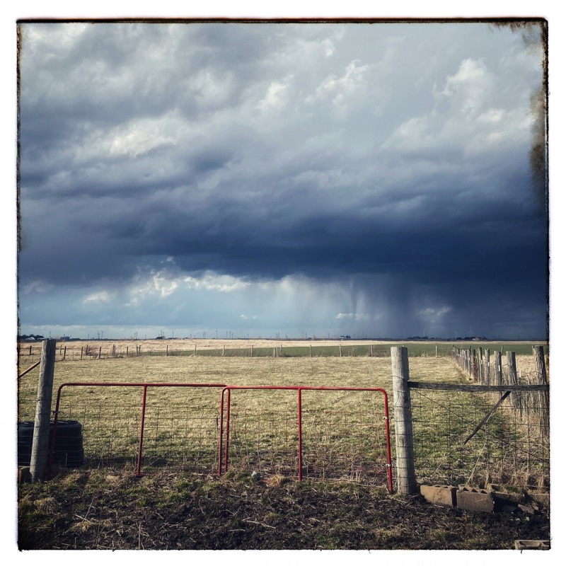 Sky. Midwest plains. Stormy sky with rain far off at the horizon. Winter fields with greening wheat. 