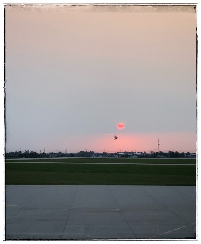moon reflecting the rising sun across an airport tarmac