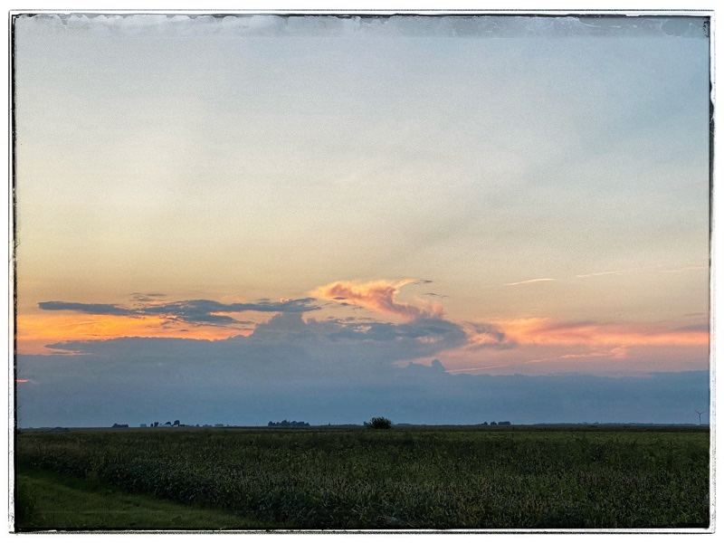 sky at sunset across fields with clouds at the horizon