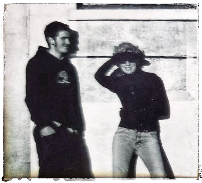 Old black-and-white photograph of woman and man woman is shielding, her face from the bright sun