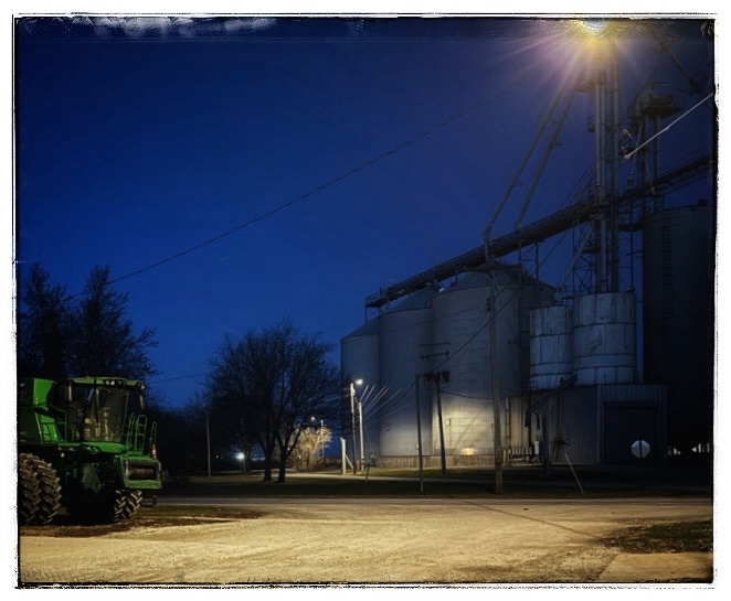 Small Midwest town at night industrial buildings, and big John Deere tractor
