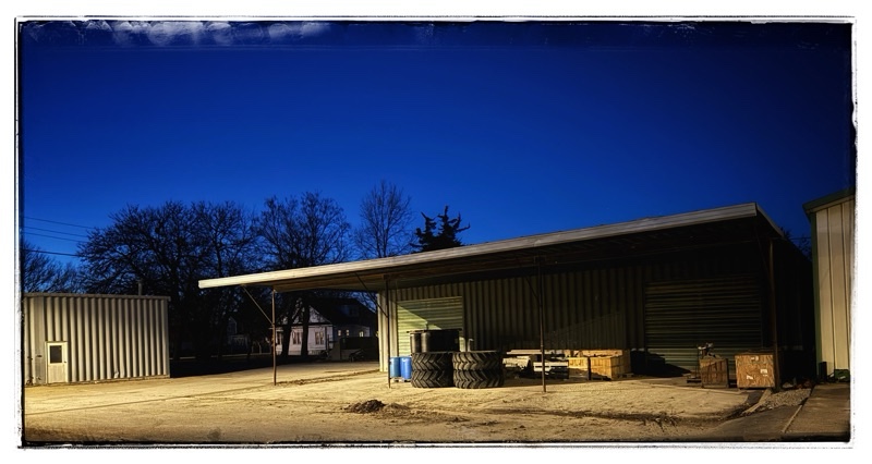 Small Midwest town at night and lights small workshop with tires sitting outside